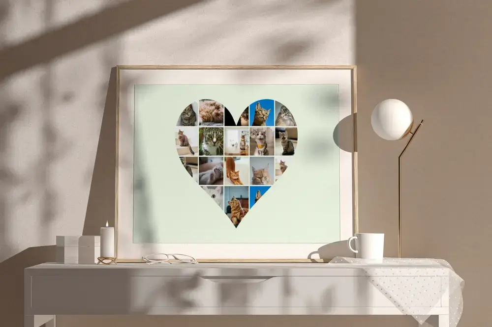 Collage di gatti a cuore su fondo verde chiaro, in cornice di legno su una credenza bianca accanto a una lampada
