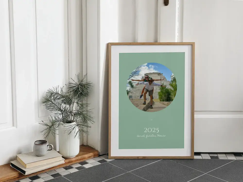 Poster di viaggio incorniciato con foto ovale su verde salvia, appoggiato a terra, regalo ricordo delle vacanze