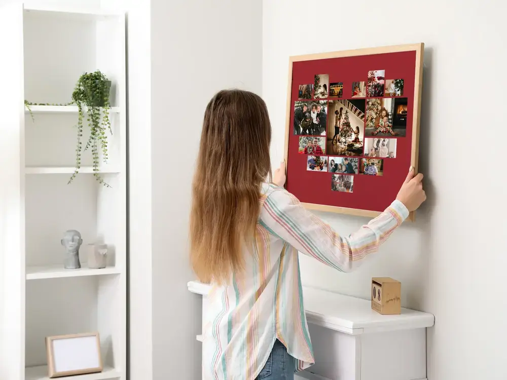 Collage di foto a cuore su fondo rosso scuro, incorniciato su parete chiara, un regalo di Natale per la famiglia