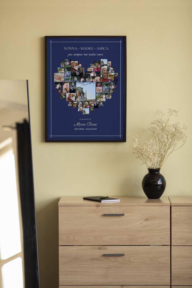 Collage commemorativo a cuore su fondo blu scuro, in cornice nera sopra una cassettiera in legno