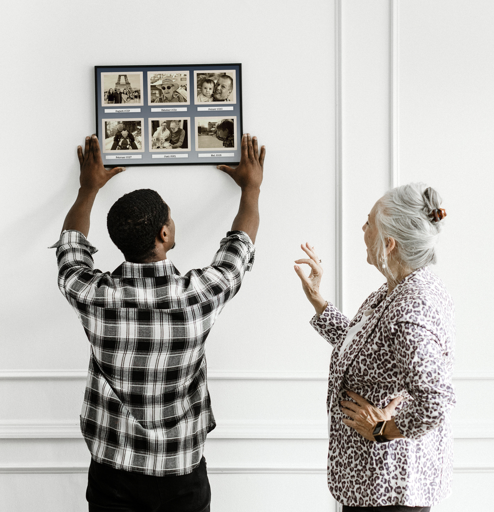 Collage rétro di 6 foto di famiglia seppia con date, in cornice nera su una parete bianca con modanature